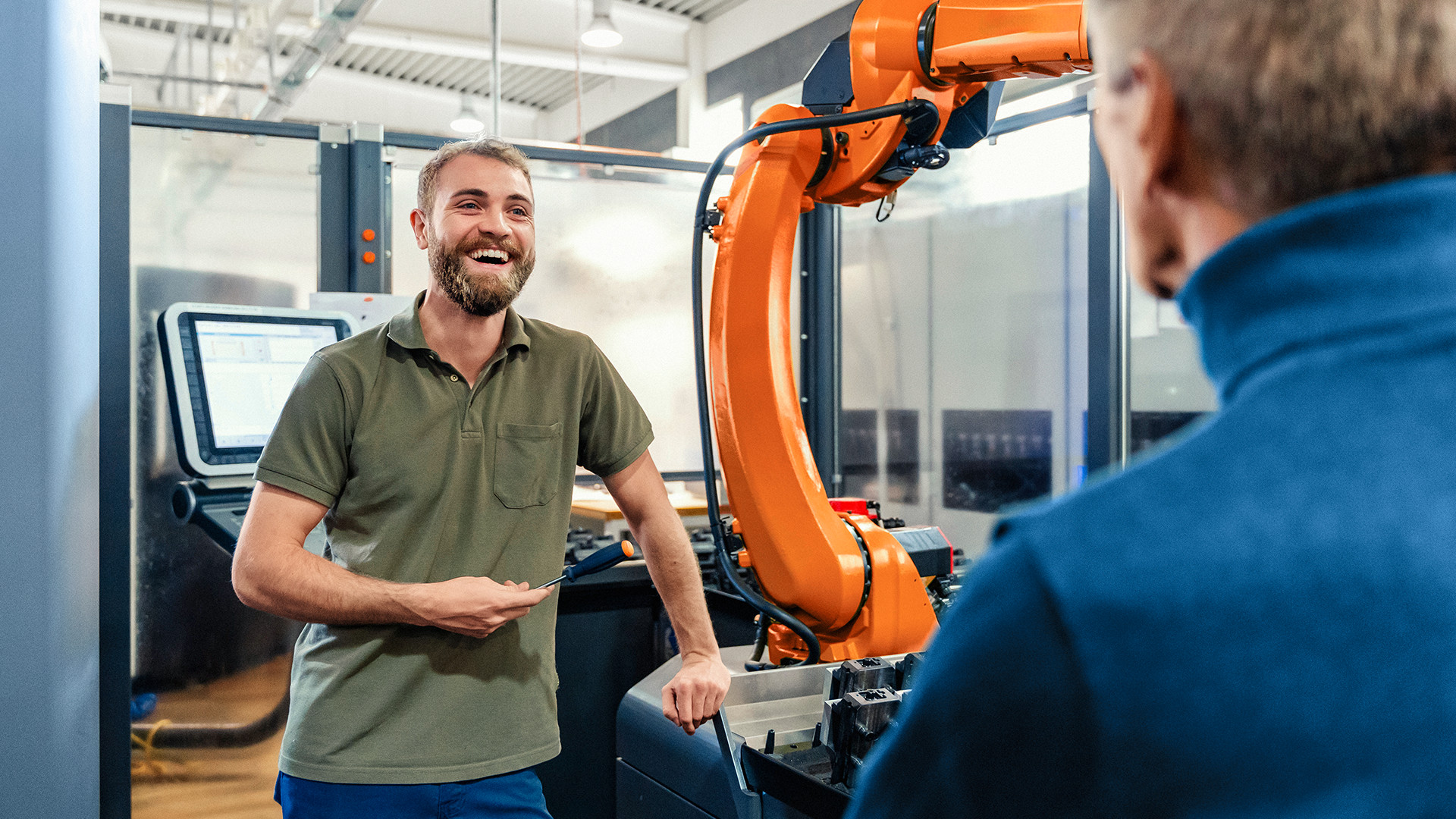 Ein Mann steht lachend vor einem Roboter. 