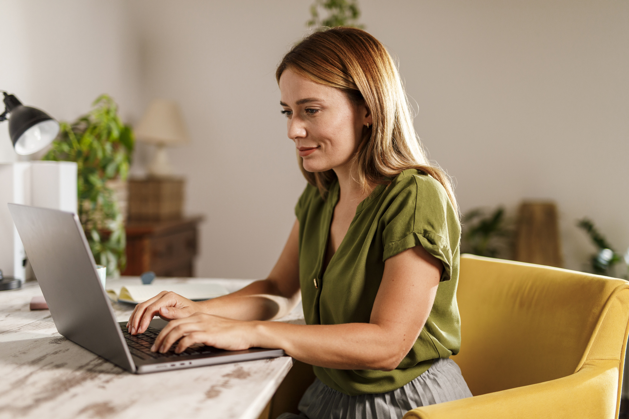 Eine Frau sitzt an einem Laptop in ihrem zu Hause