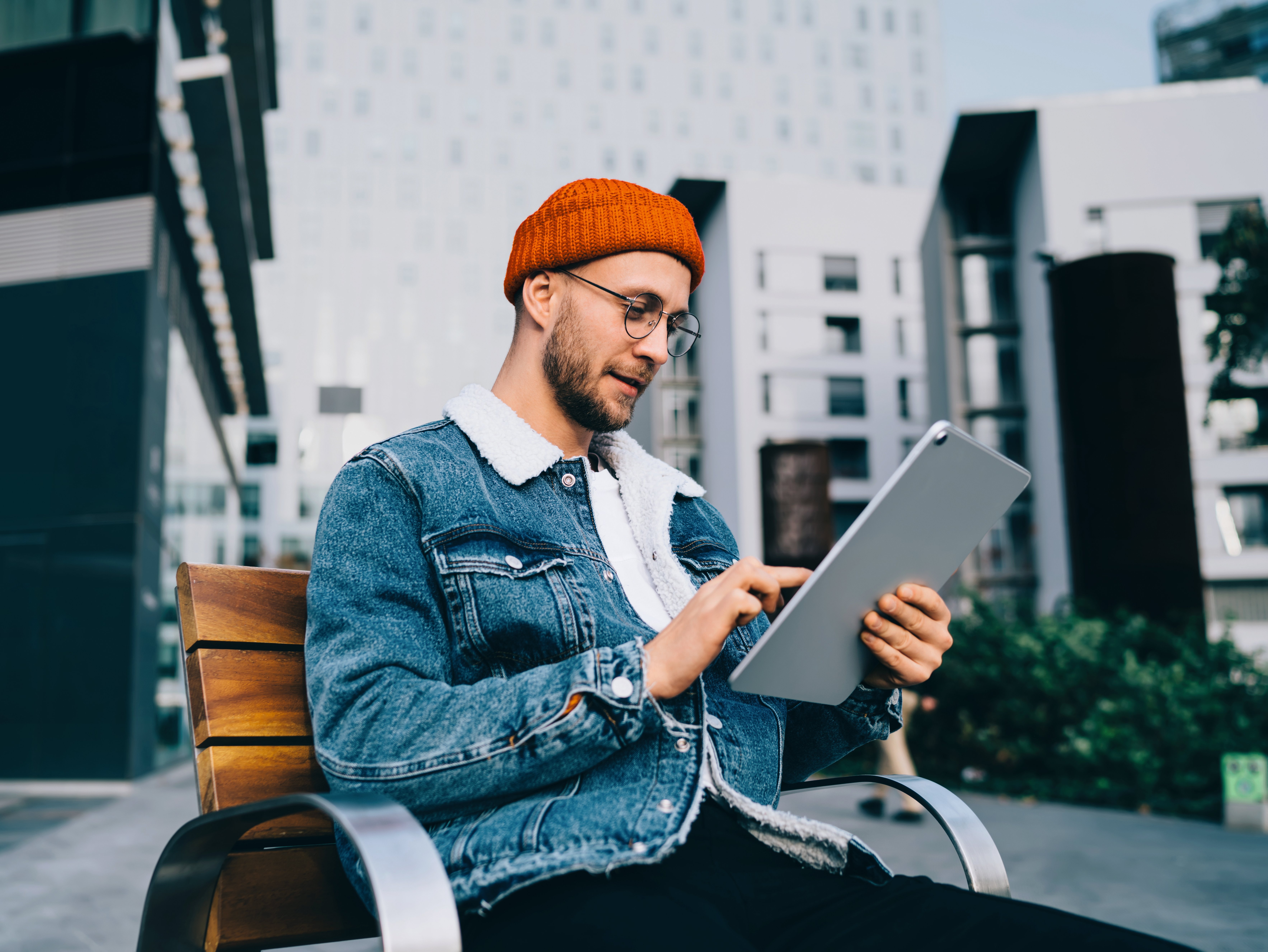 Junger Mann sitzt auf Bank mit Tablet